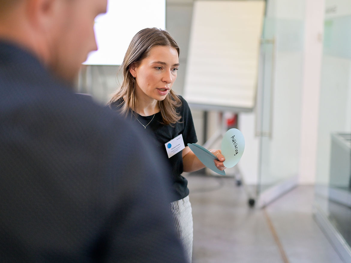 Impression aus Workshop 3 „Suchtprävention und psychische Gesundheit“ Eine Teilnehmende hält eine Antwortkarte in der Hand. Im Vordergrund steht ein Mann.