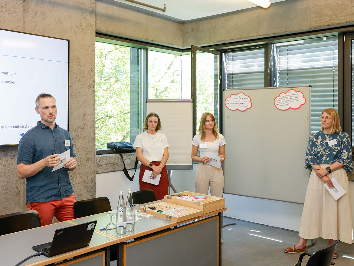 Impression aus Workshop 1 „Länderperspektive – Psyche und Gesundheit“ Vier Moderierende des Workshops „Länderperspektive – Psyche und Gesundheit“ stehen an einer Moderationstafel.