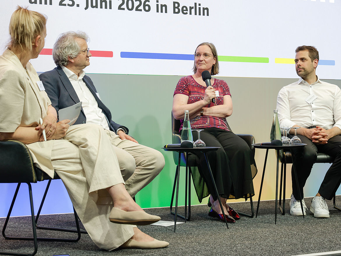Fishbowl mit Moderatorin Ibald, Vorsitzendem Vorsitzender Sozialversicherung für Landwirtschaft, Forsten und Gartenbau Jörg Heinel und Referierenden Dr. Wegewitz und Prof. Dr. Thiemann. Auf dem Podium sitzen eine Moderatorin, der Vorsitzende der Sozialversicherung für Landwirtschaft, Forsten und Gartenbau sowie zwei Referierende und disktieren.